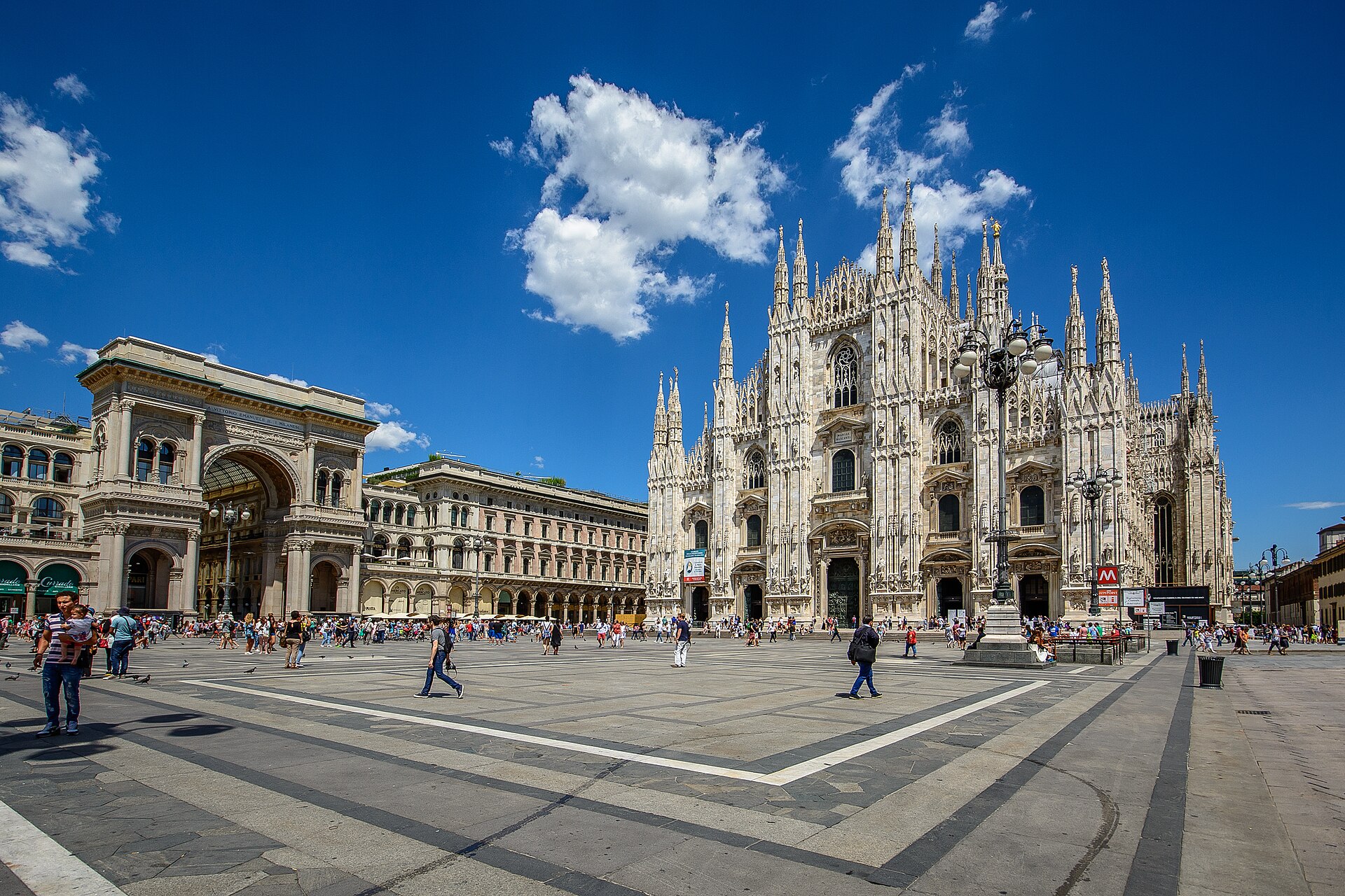 Piazza del Duomo a Milano sotto un cielo azzurro — il Duomo e l'ingresso della Galleria Vittorio Emanuele II